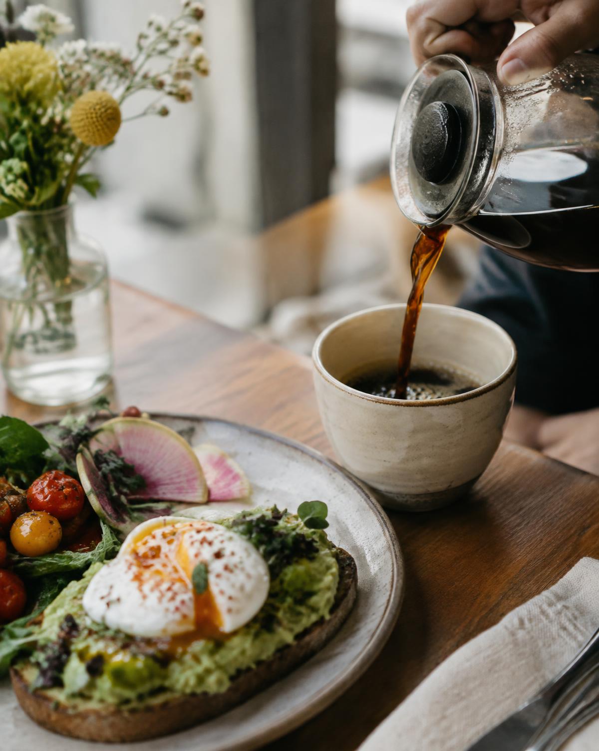 Coffee being poured beside avocado toast at Hash House